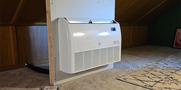 Floor-mounted ductless mini-split unit installed low on the wall of a finished attic